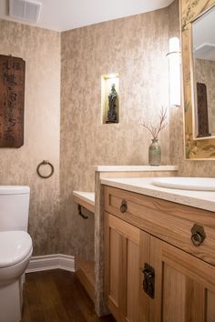 a bathroom with a toilet, sink and mirror in it's center piece is shown