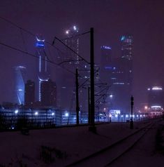 the city skyline is lit up at night, with power lines running through it and buildings in the background