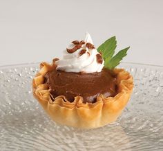 a chocolate dessert with whipped cream and mint leaves on the top is sitting on a glass plate