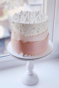 a white and pink cake sitting on top of a window sill