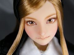 a doll with long blonde hair wearing a black jacket and white shirt is looking at the camera