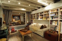 a living room filled with lots of furniture and bookshelves next to a window