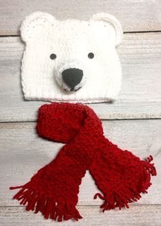 a crocheted polar bear hat and scarf on top of a white wooden background