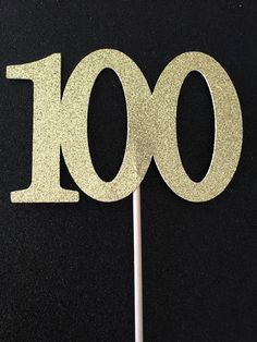 a cake topper with the number 100 on it's stick in front of a black background