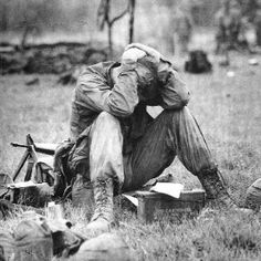 an old black and white photo of two men sitting on the ground with their heads in their hands