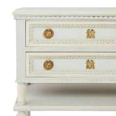 a white dresser with two drawers and gold knobs on the top, against a white background