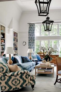 a living room filled with lots of furniture and bookshelves next to a window