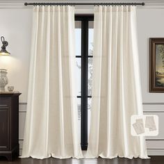 a white curtain hanging on the side of a window next to a wooden dresser and lamp