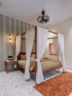 a four poster bed with white drapes on the top and curtains hanging from the ceiling