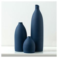 two dark blue vases sitting on top of a white table next to each other