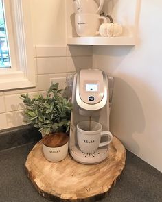 a coffee maker sitting on top of a wooden table next to a potted plant