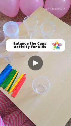 a table with plastic cups and straws for kids to play on the floor in front of balloons