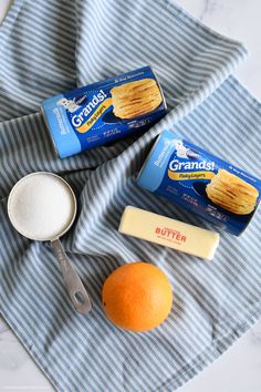 an orange, butter, and other ingredients are sitting on a blue striped towel next to a measuring cup