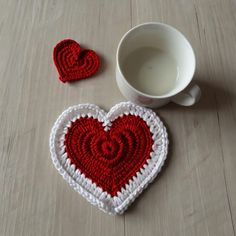 two crocheted heart coasters next to a cup of coffee