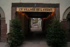 an entrance to the village de l'avent with christmas lights strung over it