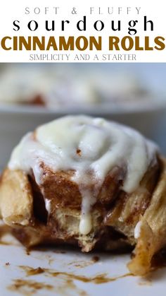 a cinnamon roll with icing sitting on top of a white plate next to a bowl