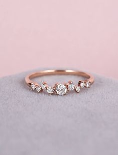 a rose gold ring with three small diamonds on the side, sitting on top of a rock