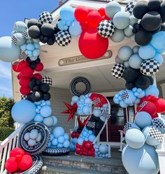 the entrance to a house decorated with balloons and checkered flags for an upcoming birthday party