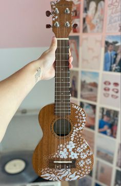 a person holding an ukulele in front of a wall with pictures on it