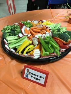 a platter full of vegetables sits on an orange table cloth with a sign that says farmer's all veggies