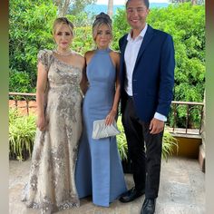 two women and a man standing next to each other in formal wear at an event