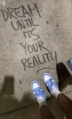 someone is standing on the sidewalk with their feet up in front of them and writing on the pavement