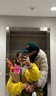 a man and woman taking a selfie in an elevator with flowers on the floor