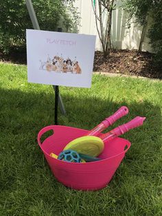 there is a pink bowl with toys in it and a sign that says play fetch