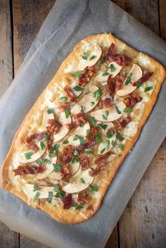 a pizza with mushrooms and bacon on it sitting on top of a piece of wax paper