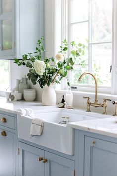 a white kitchen sink sitting under a window next to a vase with flowers in it