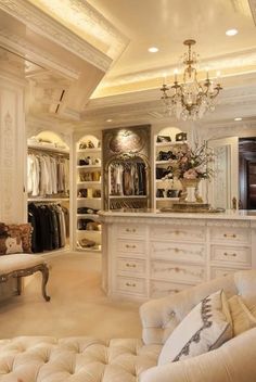 an elegant closet with white furniture and chandelier hanging from the ceiling in front of it