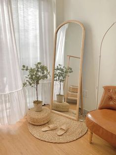 a living room with a chair, mirror and potted plant on the floor in front of it