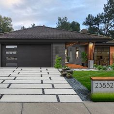 a house with a large driveway in front of it and landscaping on the other side