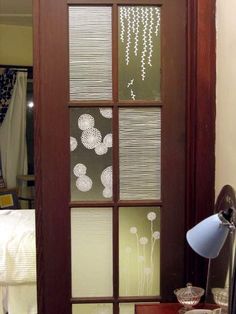 a room with a bed, desk and glass doors that have flowers drawn on them