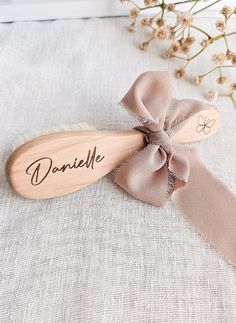 a wooden spoon with a name on it and a bow tie around the spoon's edge