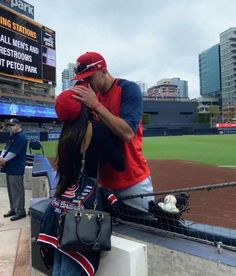 a man and woman are sitting on the bench at a baseball game, one is covering his face with her hand