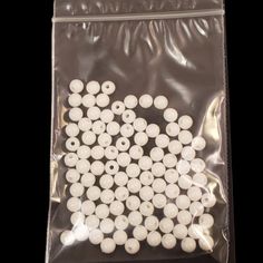 white plastic buttons in a bag on a black background