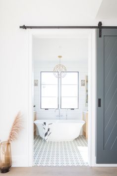 a white bath tub sitting inside of a bathroom next to a wooden floor and door