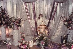 an elaborately decorated room with flowers, candles and vases on the floor in front of sheer curtains