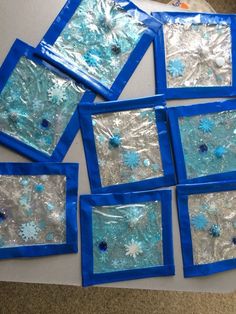 several pieces of blue and silver foil with snowflakes in them on a table