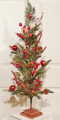 a small christmas tree with red ornaments and pine cones