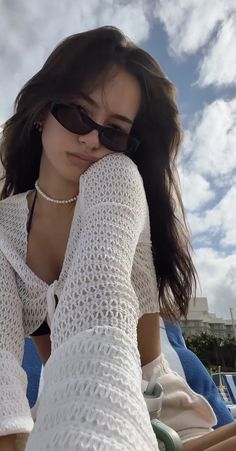 a woman wearing sunglasses sitting on top of a beach chair