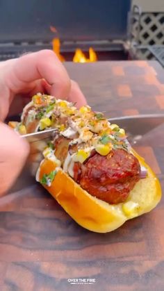 a person cutting into a hot dog with toppings