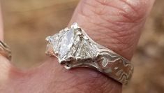 a close up of a person's hand wearing a ring with a diamond on it