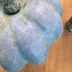 a blue pumpkin sitting on top of a wooden table next to a brown and white cat