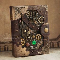 an old book with gears and jewels on it sitting on a table next to a wall