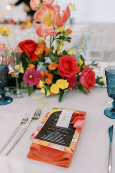 the table is set with colorful flowers and silverware