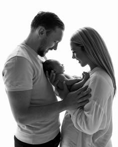 a man and woman holding a baby in their arms