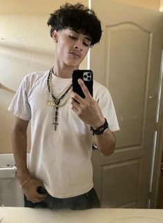 a young man is taking a selfie in the mirror with his cell phone and wearing a necklace