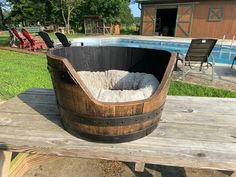 a wooden barrel sitting on top of a table next to a swimming pool with chairs around it